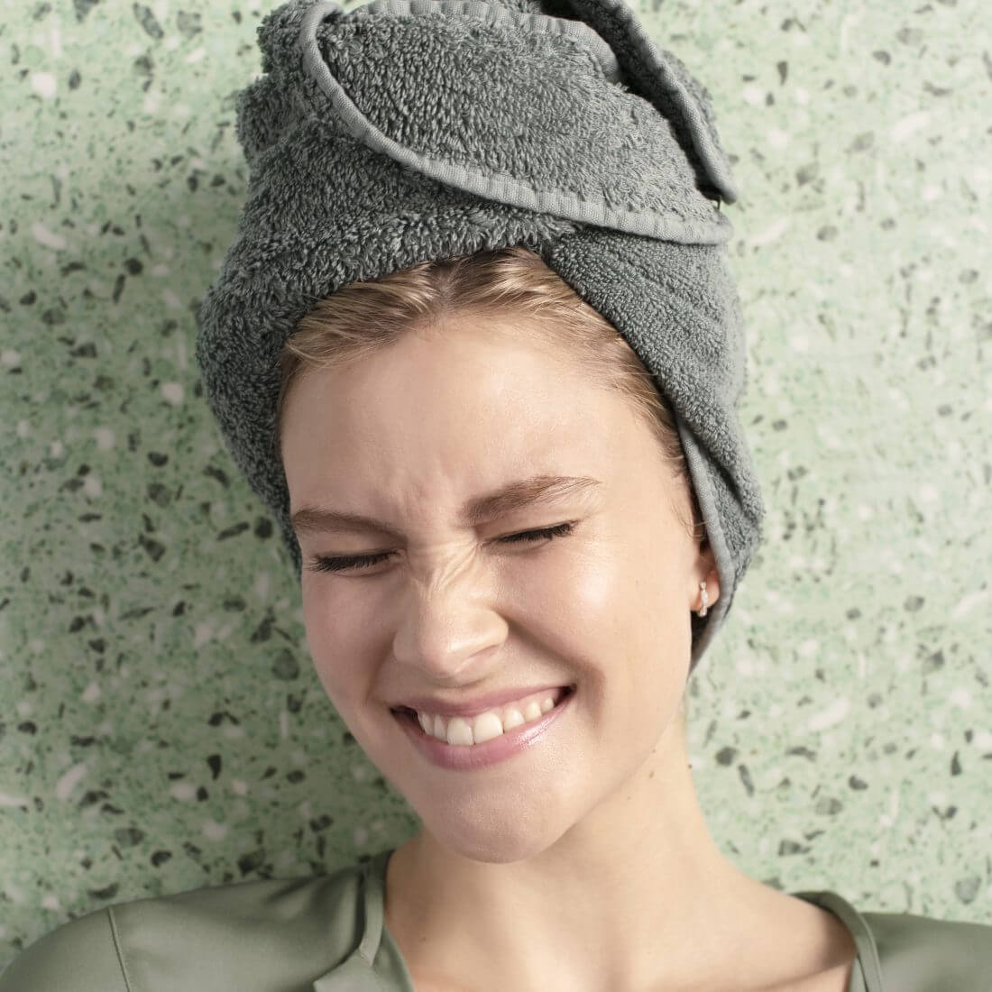 Young woman with her hair in a towel with eyes closed tightly