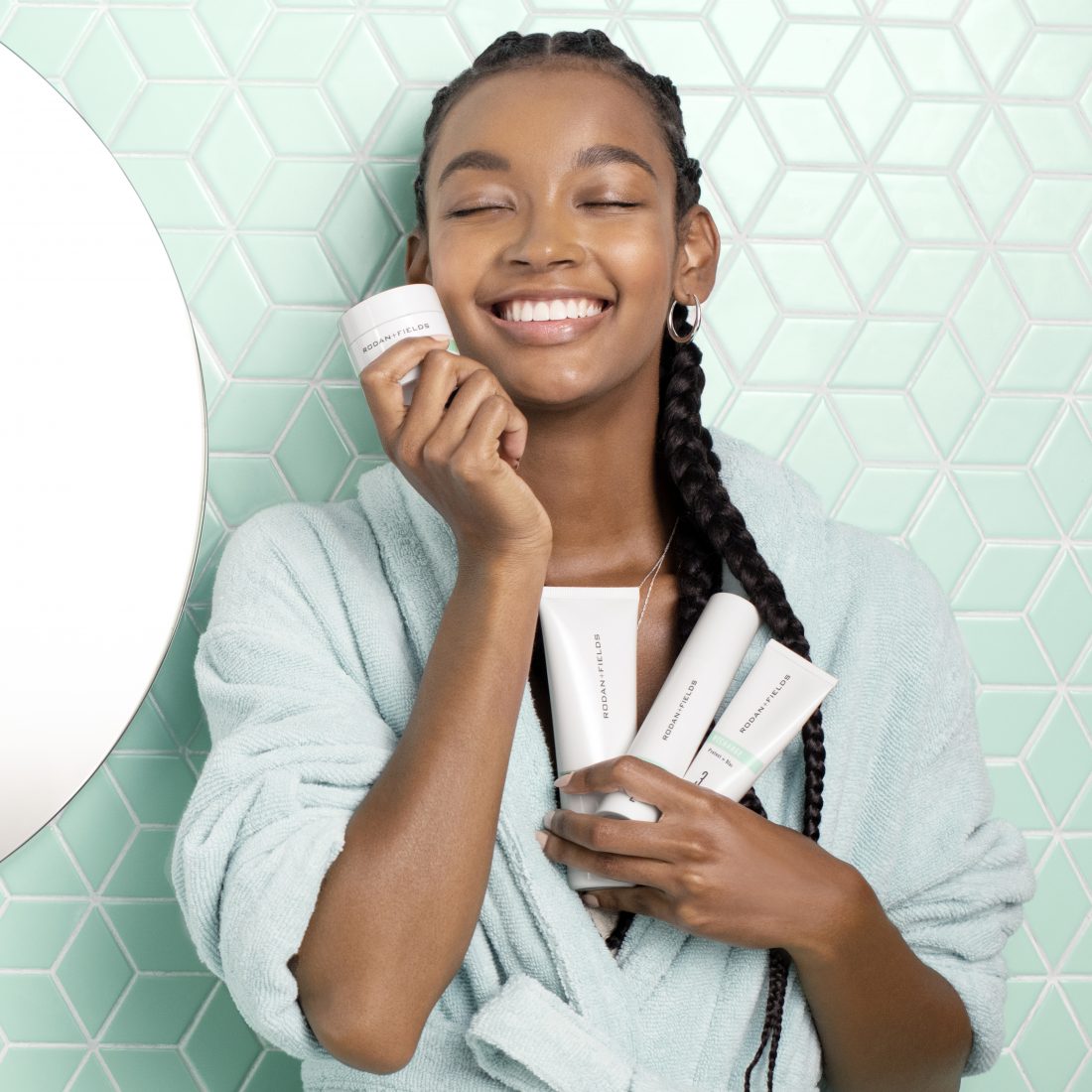 Young woman with dark skin holding Recharge Detox Mask and Regimen